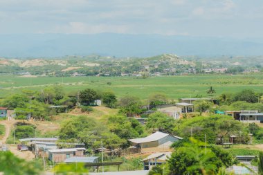 Birkaç evi ve birkaç ağacı olan bir kırsal bölge. Evler küçük ve ağaçlar yeşil.