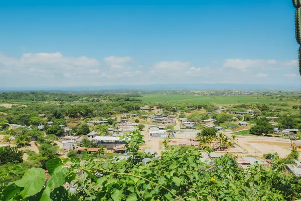Uzakta küçük bir kasabası olan kırsal bir bölge. Gökyüzü açık ve mavi. Kasaba yemyeşil bir tarla ile çevrili.
