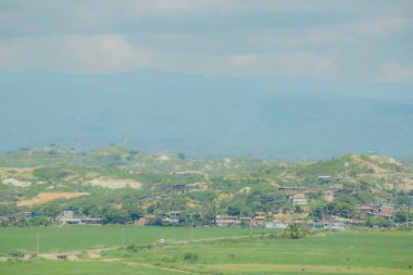 Birkaç evi ve birkaç insanı olan bir kırsal bölge. Gökyüzü bulutlu ve arka planda dağlar var