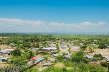 Bir sürü evi ve bir kaç ağacı olan küçük bir kasaba. Gökyüzü mavi ve bazı bulutlar var.