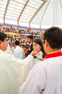 Tumbes, Tumbes, Peru 21-10-2023, Doğrulama Ayini: Bir rahip genç bir kadını kutsuyor. Rahip beyaz bir bornoz giyiyor ve kadın beyaz bir gömlek giyiyor. Rahip elinde bir parça ekmek tutuyor ve kadın da...