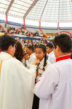 Tumbes, Tumbes, Peru 21-10-2023, Doğrulama Ayini: Bir rahip genç bir kızı kutsuyor. Rahip beyaz bir bornoz giyiyor ve kız beyaz bir gömlek giyiyor. Rahip kızın elini tutuyor.