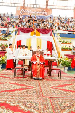 Tumbes, Tumbes, Peru 21-10-2023, Doğrulama Ayini: Kırmızı cüppeli bir adam büyük bir kalabalığın önünde oturuyor. Adam bir rahip ve kalabalık dini bir etkinlik için toplandı.