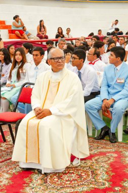 Tumbes, Tumbes, Peru 21-10-2023, Doğrulama Ayini: Beyaz cüppeli bir adam kalabalığın önünde oturuyor. O bir kravat ve beyaz bir bornoz giyiyor.