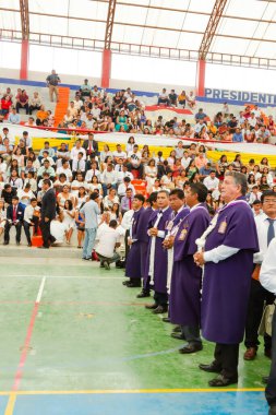 Tumbes, Tumbes, Peru 21-10-2023, Onaylama Ayini: Mor cüppeli bir grup adam stadyumda duruyor. Kalabalık onları izliyor. Adamlar mor cübbe giyiyor ve kuyrukta bekliyorlar.