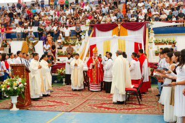Tumbes, Tumbes, Peru 21-10-2023, Doğrulama Ayini: Bir grup insan kırmızı cüppeli bir adamın etrafında toplandı. Adam bir rahip ve insanlar bakıyor.