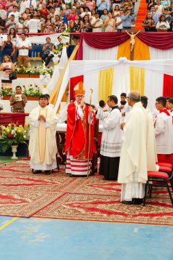 Tumbes, Tumbes, Peru 21-10-2023, Onaylama Ayini: Bir grup rahip, beyaz haç tutan kırmızı cüppeli bir adamla masanın etrafında toplandı.