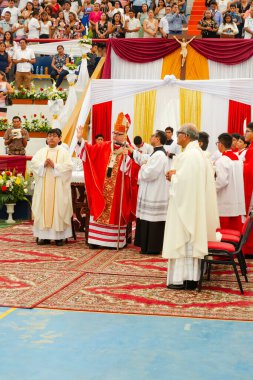 Tumbes, Tumbes, Peru 21-10-2023, Onaylama Ayini: Bir grup rahip, beyaz haç tutan kırmızı cüppeli bir adamla masanın etrafında toplandı.