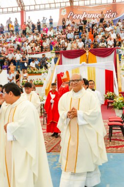 Tumbes, Tumbes, Peru 21-10-2023, Ayin Ayini: Beyaz cüppeli bir adam kırmızı halıda yürüyen ve izleyen bir kalabalık. Bu adam bir rahip ve bu olay dini bir tören.