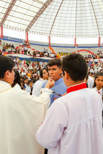 Tumbes, Tumbes, Peru 21-10-2023, Onaylama Ayini: Bir rahip mavi gömlekli genç bir adamı kutsuyor. Rahip beyaz bir bornoz giyiyor ve genç adam mavi bir gömlek giyiyor.
