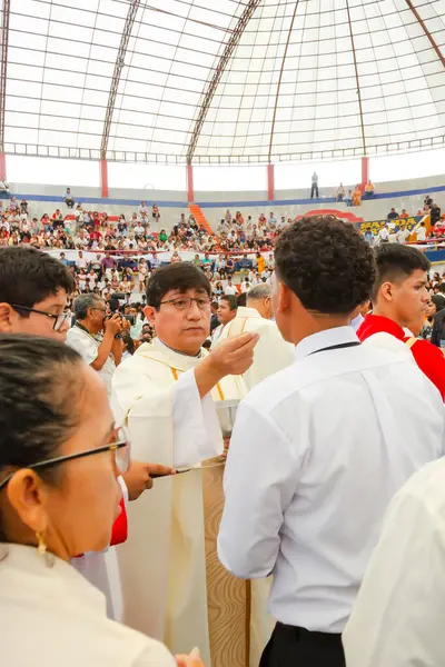 Tumbes, Tumbes, Peru 21-10-2023, Doğrulama Ayini: Beyaz gömlekli bir adam bir grup insana el hareketi yapıyor. İnsanlar büyük bir stadyumda toplandı ve adam bir rahip. Atmosfer canlı ve enerjik.