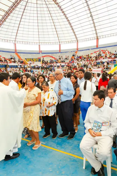 Tumbes, Tumbes, Peru 21-10-2023, Ayin Ayini: Bir stadyumda büyük bir kalabalık toplandı ve bazıları sandalyede oturuyor. Beyaz cüppeli bir adam kalabalığın önünde duruyor ve bir kadın elinde bir kitap tutuyor.