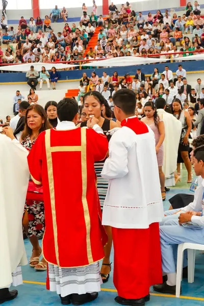 Tumbes, Tumbes, Peru 21-10-2023, Onaylama Ayini: Bir rahip kırmızı cüppeli bir kadını kutsuyor. Rahip kırmızı bir bornoz ve altın bir haç giyiyor. Kadın beyaz bir elbise giyiyor. Sahne büyük bir P kalabalığında geçiyor.