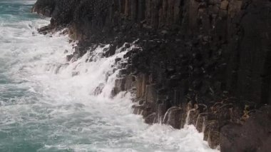 Dalgalanmalar, ardından daha büyük dalgalar, ikonik altıgen sütunlarıyla bazalt kayalıklara çarpar, sonra da Avustralya 'nın New South Wales şehrinde popüler bir turistik bölge olan Fingal Head' de kayalıklardan aşağı koşar..