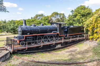 Emekli eski bir buharlı lokomotif ve kömür kamyonu, Queensland, Avustralya 'daki Imbil' de ağaçların ve gökyüzünün arka planına karşı trenin son safhasında dönmesi için kullanılıyor..