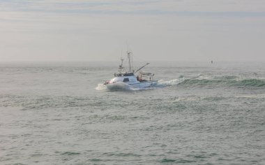 Bir balıkçı teknesi, Queensland, Avustralya 'daki Gold Coast, Avustralya' daki Seaway 'deki limanına dönerken liman girişindeki tehlikeli bölgede dalgalar halinde dalgalanırken, pruvasını suya sürüyor..