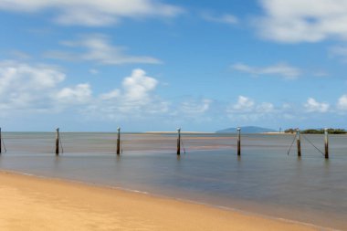 Avustralya 'nın Queensland kentinde Taylor' s Beach 'teki Mercan Denizi' nde bulutlu mavi gökyüzü ve açık deniz adalarının arka planına karşı sakin bir girişte olası bir eski yüzme havuzu..