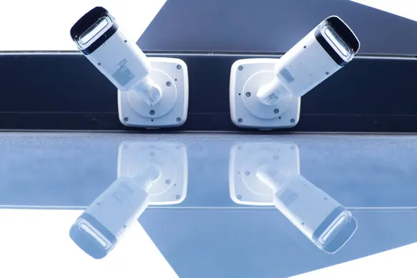 Bir blu üzerine monte edilmiş iki modern güvenlik kamerasının simetrik görüntüsü