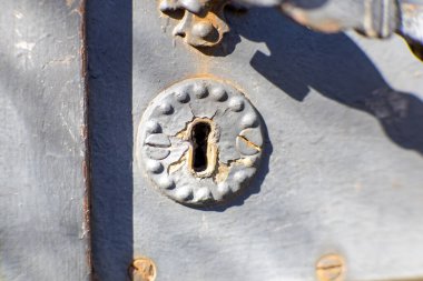 Eski, paslı bir anahtar deliğine yakın çekimde yıpranmış metal bir kapının üzerinde. Eskimiş doku ve ezgi gizem, tarih ve nostalji duygusunu çağrıştırıyor. Güvenlik, sırlar ve klasik estetik konuları için ideal.