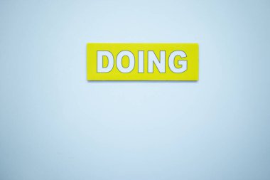 Beyaz arka planda, devam etmekte olan görevleri temsil eden sarı bir DOING etiketi. Kanban ve Agile gibi görev yönetim sistemlerinde aktif olarak yapılan çalışmaları izlemek için kullanılır. Yüksek kalite fotoğraf