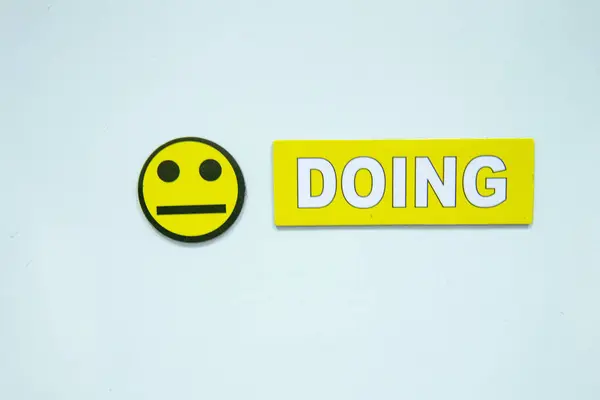 Nötr yüzlü sarı bir emoji ve temiz beyaz arka planda koyu sarı bir Ding yazısının yer aldığı minimalist bir kompozisyon. Yüksek kalite fotoğraf