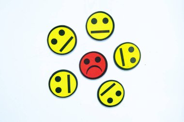 Duygusal dinamiğin görsel bir temsili. Merkezi kırmızı üzgün yüz, izolasyonu, sosyal baskıyı, duygusal dengesizliği veya karar verme mekanizmasını sembolize eden altı nötr sarı yüzle çevrilidir.