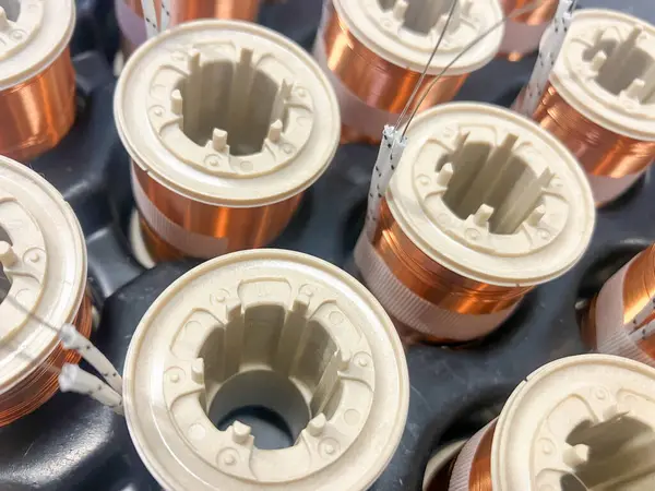 Endüstriyel bakır bobinlere yakın çekim, titizlikle silindirik çekirdeklerin etrafına sarılmış. Görüntü, modern çağda duyarlılık mühendisliği, elektrik iletkenliği ve estetik üretimi sergiliyor.