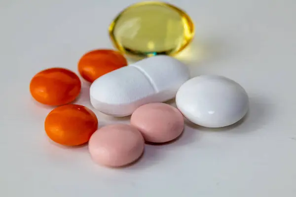 Beyaz arka planda çeşitli renkli haplar ve kapsüller. Sağlık ve sağlık kavramları için farklı şekil ve renklerde vitamin, takviye ve ilaç.