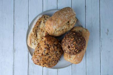 Tahıllı ve tahıllı ekmekli bir tabağın yukarıdan görünüşü, kırsal beyaz ahşap bir masa üzerine yerleştirilmiş..