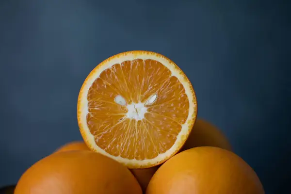 Taze portakal ikiye bölünmüş ve sulu dokusunu koyu mavi arka planda ortaya çıkarmış. Canlı ve ferahlatıcı.