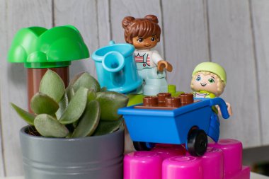 Bahçede bitkiler ve aksesuarlarla oynayan renkli plastik oyuncaklar. Çocuklar için eğlenceli ve eğitici bir kavram.