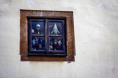Tarihi bir bina duvarında desenli taş bir çerçeveye yerleştirilmiş küçük cüce ve oyuncak heykelcikleri olan eski vitrin..