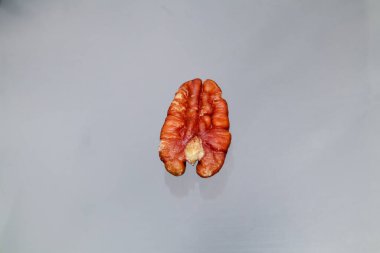 Açık arkaplandaki tek bir kırmızı ceviz, doğal dokuyu ve rengi gösteriyor..