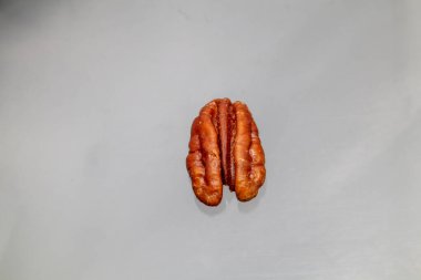 Beyaz arka planda bir ceviz kabuğunun doğal dokusunu ve kırmızımsı kahverengi rengini vurgulayan makro görüntüsü..