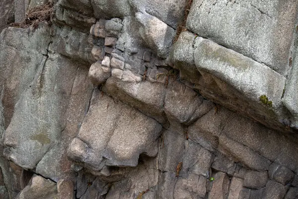 Doğal çatlaklara ve dokulara sahip yıpranmış kaya duvarına yakın çekim. Engebeli bir dağ ortamında jeolojik katmanlar ve erozyon gösteren ayrıntılı taş yüzeyler..
