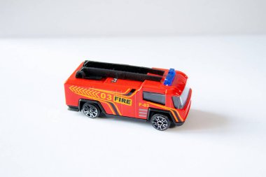 Beyaz arka planda kırmızı oyuncak itfaiye aracı, yan görüş. Çocuk oyuncular veya model koleksiyoncular için ayrıntılı minyatür araç.