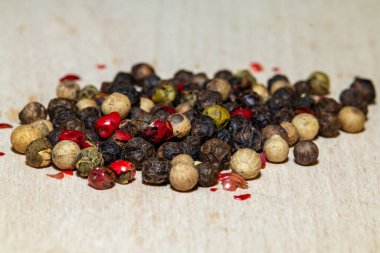 Biberli, siyah, beyaz, yeşil ve kırmızı biberlerin Aromatik karışımı hafif kumaşa saçılmış. Yakın plan bir yemek fotoğrafında parlak kontrast, doku ve aşçılık ayrıntıları.