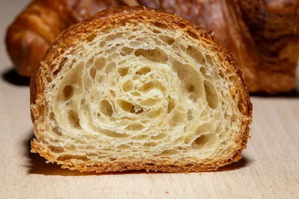 Dilimlenmiş kruvasanın yakın çekimi, altın, pul pul, havadar, katmanlı iç yüzeyini gösteriyor. Zanaatkar hamur işi dokusunun ayrıntılı görünümü.