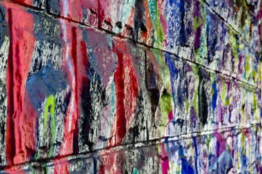 Renkli, renkli bir duvara yakın plan. Canlı graffitilerin damlayan katmanlarıyla kaplı. Bu da desenli, soyut bir sokak sanatı kompozisyonu oluşturuyor..