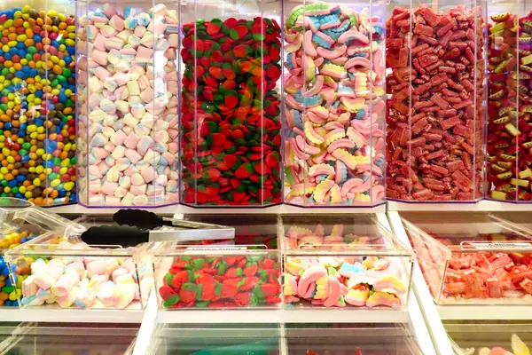 Şekerci dükkanındaki şeffaf kaplarda renkli şekerler sergileniyor. Şekerleme çeşitleri, şekerlemeler ve parlak renklerde tatlılar..