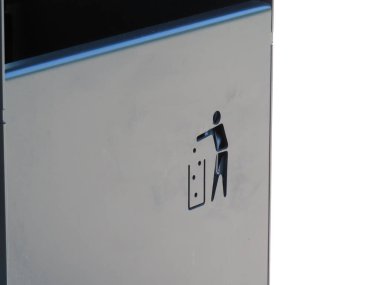 Gümüş metal bir yüzey üzerindeki çöp tenekesinin yakın çekimi, atık imhayı sembolize ediyor. Çevresel farkındalığı teşvik eden minimalist şehir tasarımı.