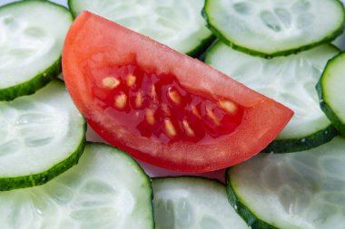 Salatalık dilimlerine yerleştirilmiş taze bir domates diliminin yakın çekimi, sağlıklı yemek kavramları için mükemmel..