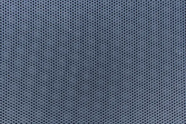 Eşit aralıklı yuvarlak delikleri olan metalik delikli bir levhanın yakın çekimi geometrik endüstriyel desen oluşturur..