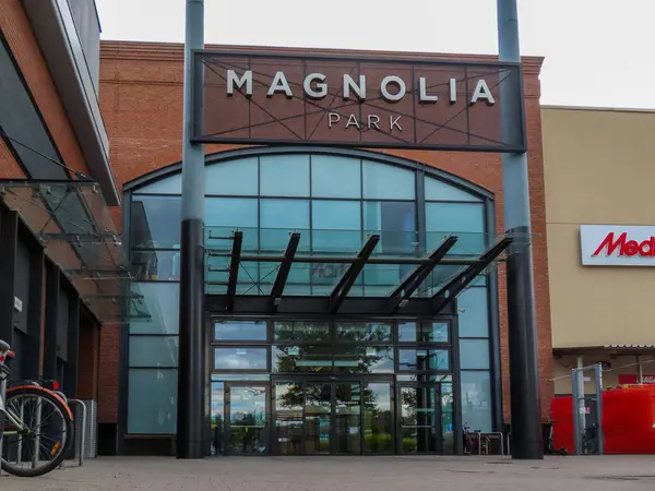 Polonya. Yılan pençesi. 29.05.2025 Wroclaw 'daki Magnolia Park alışveriş merkezinin modern cam girişi, kırmızı tuğlalı cephe, dışarıda park edilmiş bisikletler ve açık mavi gökyüzü..