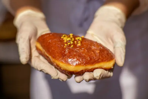 Eldivende geleneksel Polonya çöreği, turuncu jöleli ve ezilmiş şam fıstığı var. Sokak yemekleri ya da fırın konsepti, tatlı pastalar yakın plan..
