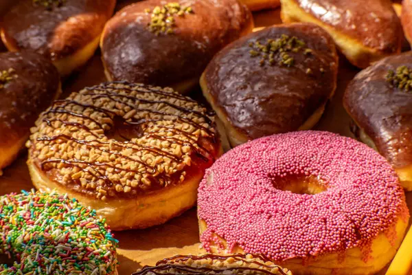 Fırında ahşap bir tepside çeşitli jöleli ve süslü çörekler, renkli malzemeler ve dokular..