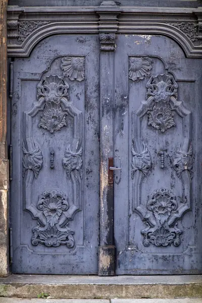 Süslü, çiçekli süslemeli ve soyulmuş boyalı antika mavi ahşap kapı. Tarihi cazibesi olan klasik mimari öğeler.