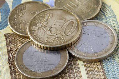 Avro banknotundaki Euro sikkelerine yakın çekim. Avrupa para biriminin 50 cent, 1 ve 2 euro arasında doku ve gravürleri gösteren ayrıntılı görünümü.