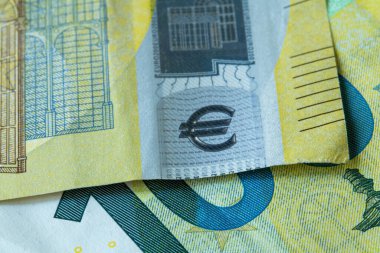 Avro banknotlarının üst üste bindirilmesi ayrıntılı güvenlik modelleri ve avro sembolünü gösteriyor. Avrupa para birimi tasarımı ve dokusunun makro görüntüsü.