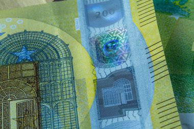 200 avroluk banknotun güvenlik özelliklerinin yakın çekimi. Hologram çizgisi, mikro baskı ve Avrupa para biriminin canlı renkli dokusu ayrıntıları.